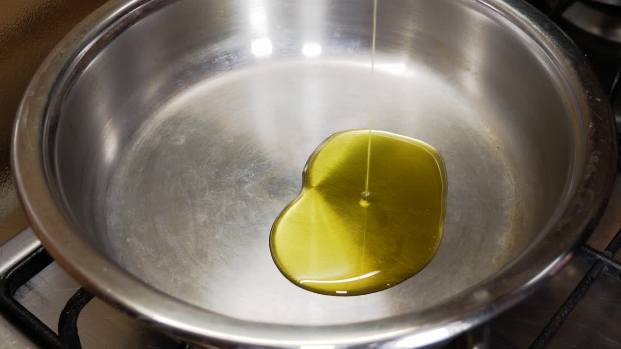 verter aceite de oliva en una olla de plata metálica de una botella de aceite en vista de cerca