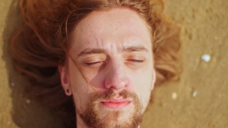 a scene of a man waking up on the beach - close up
