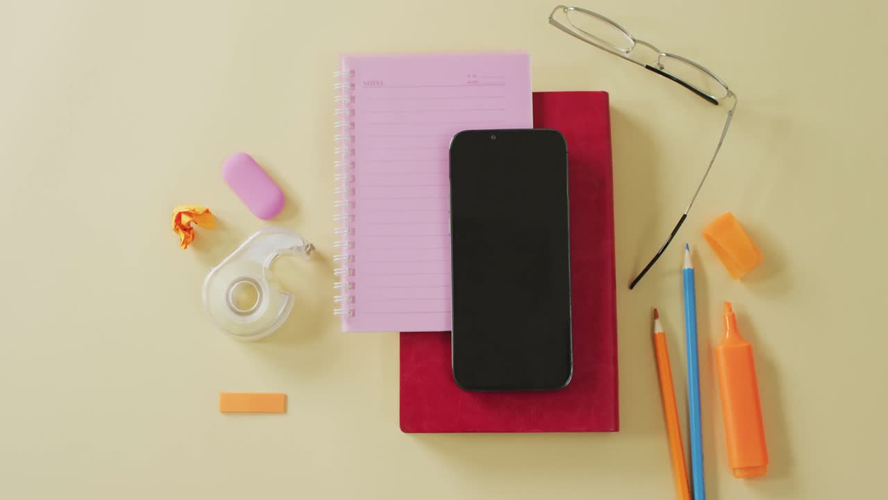 vídeo de un teléfono inteligente con espacio para copiar, cuadernos y equipos escolares sobre fondo amarillo