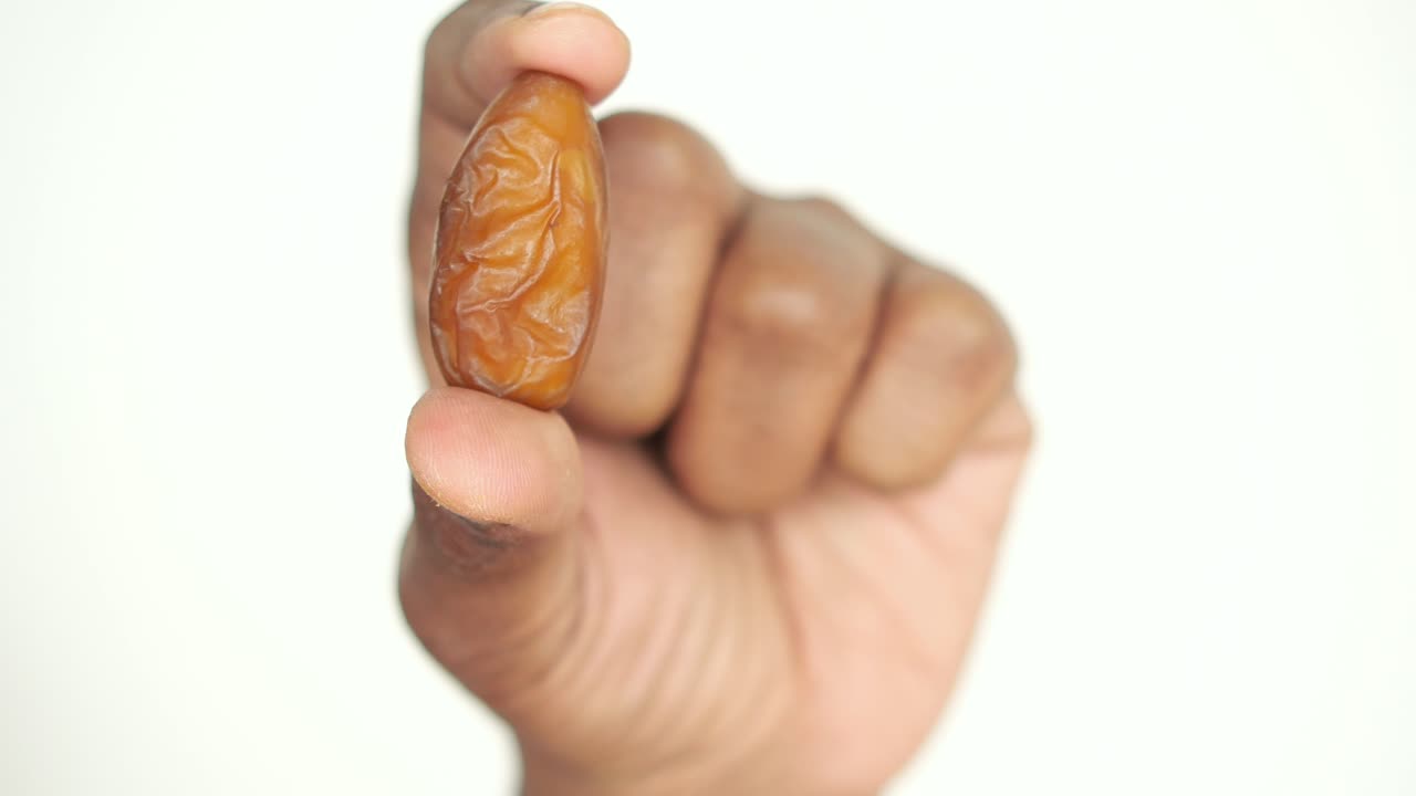 A single date fruit held between two fingers