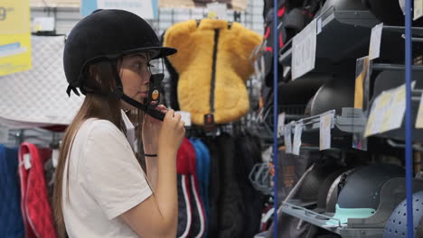 woman trying on a riding helmet in a store