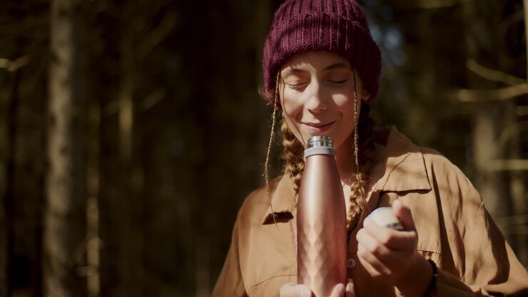 Young female tourist smelling coffee from thermos