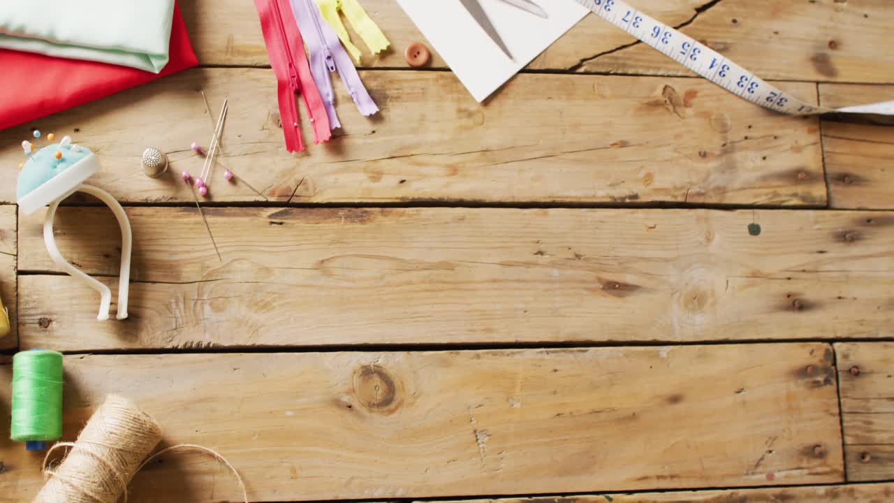 vídeo de cinta métrica, cojín de alfileres, hilos, tela y cremalleras sobre fondo de madera con espacio para copiar