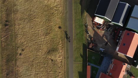 Top-down-drone-shot-of-a-horse-rider-with-another-horse,-walking-on-a-street-in-the-Netherlands