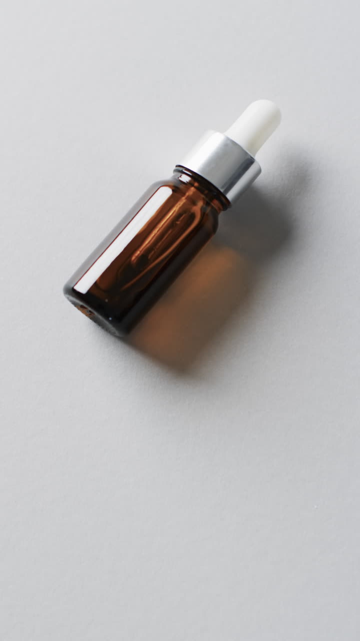 Vertical video of make up bottle with pipette and copy space on white background