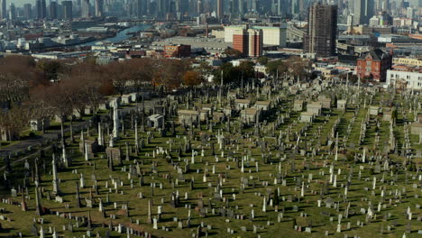 Gravestones-and-tombs-in-green-grass-on-old-Calvary-Cemetery.-Place-of-remembrance-in-urban-neighbourhood.-Queens,-New-York-City,-USA