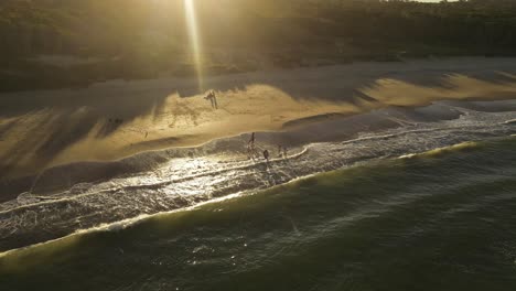 Drohnenflug-über-Den-Strand-Von-Playa-Grande-In-Uruguay,-Wo-Kinder-Bei-Sonnenuntergang-In-Den-Wellen-Spielen