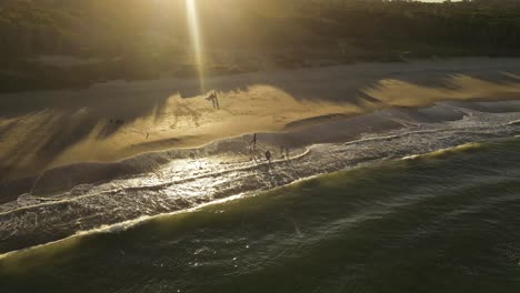 drone flight over playa grande beach in uruguay where kids play in the waves at sunset