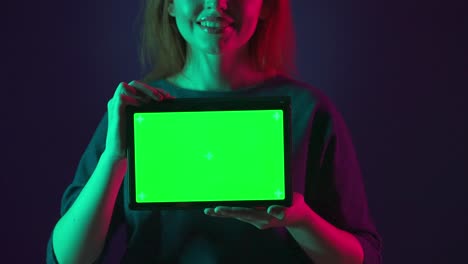 mujer sosteniendo una tableta con una pantalla verde
