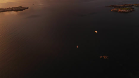 Aerial-tracking-shot-of-boats-on-the-coast-of-central-Norway,-dramatic-evening