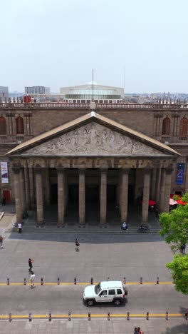 Backward vertical drone shot from Apollo sculpture to full Teatro Degollado facade and Plaza de la LIberacion in Guadalajara historic center