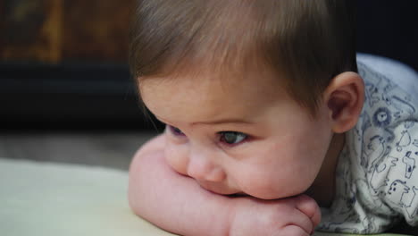 baby boy rests his head on his arm while learning how to crawl