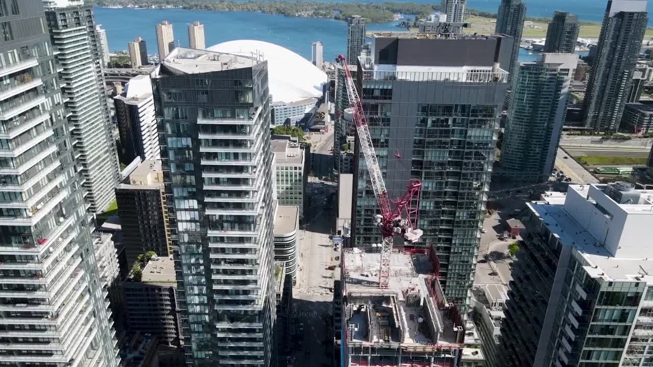 toma aérea volando a través de edificios en el centro de toronto con el lago ontario y la isla de toronto en el fondo