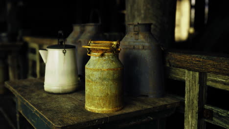 vintage milk cans on rustic wooden table in a dimly lit barn