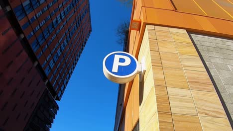 The-camera-arcs-left-around-the-parking-lot-symbol-attached-to-the-wall-of-a-downtown-Tempe,-Arizona-high-rise-building