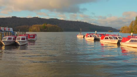 boats docked on lake windermere in the late afternoon at golden hour - from bowness-on windermere, england