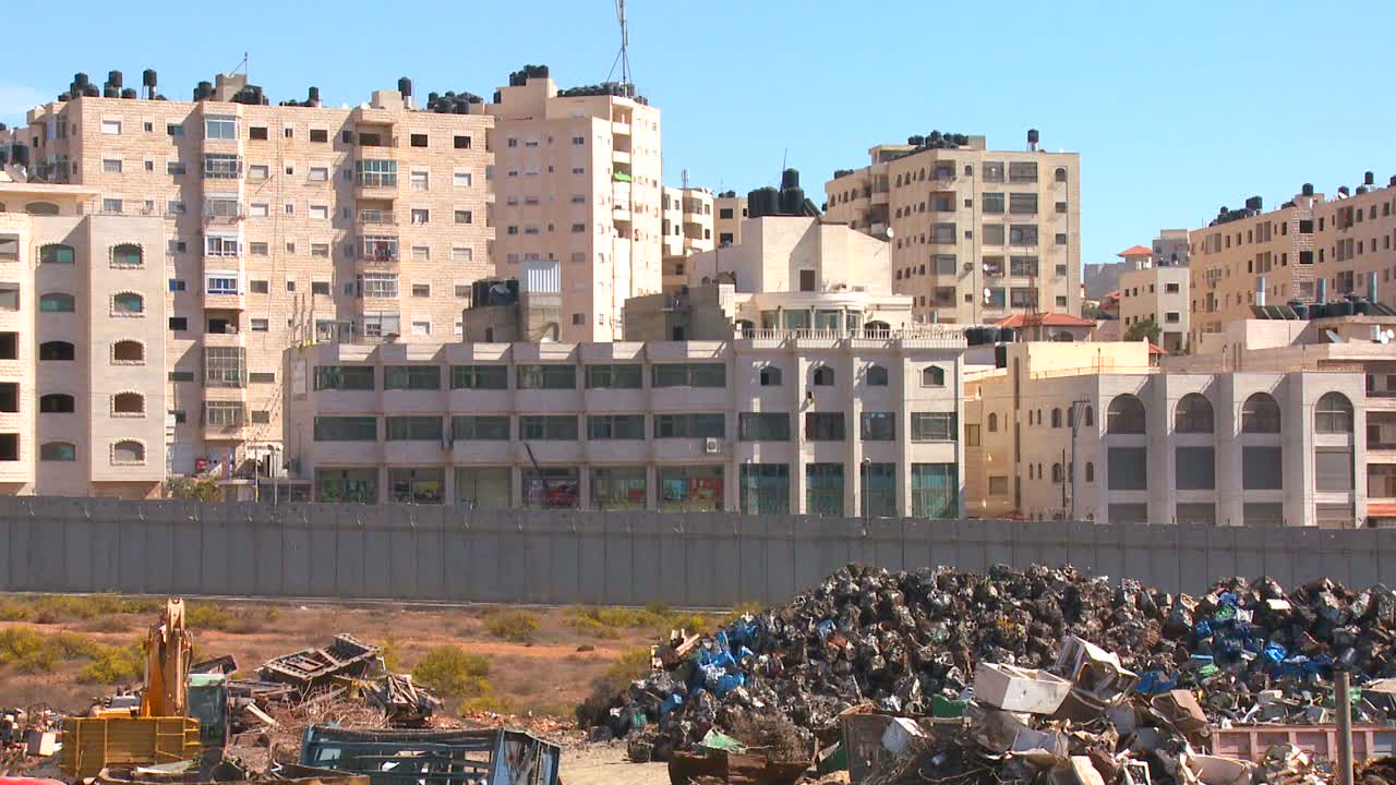 Palestinian buildings stand behind the new West Bank Barrier between Israel and the Palestinian territories