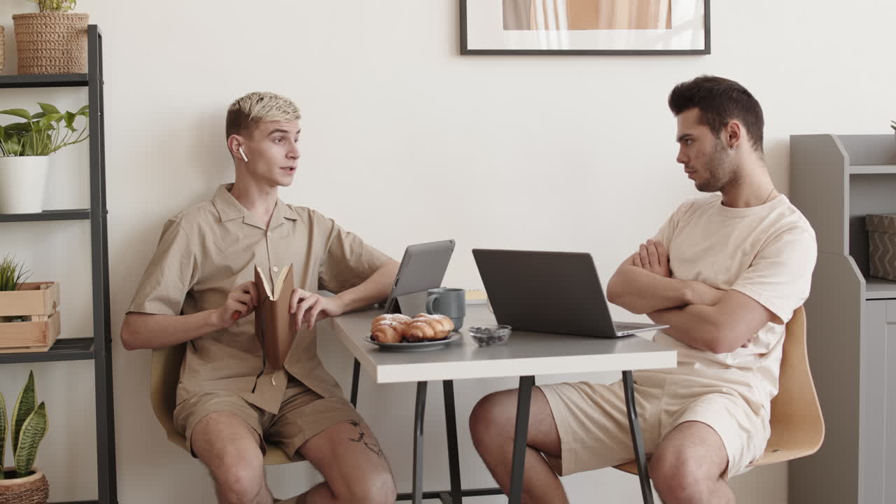 Two Men Sitting at Desktop and Chatting