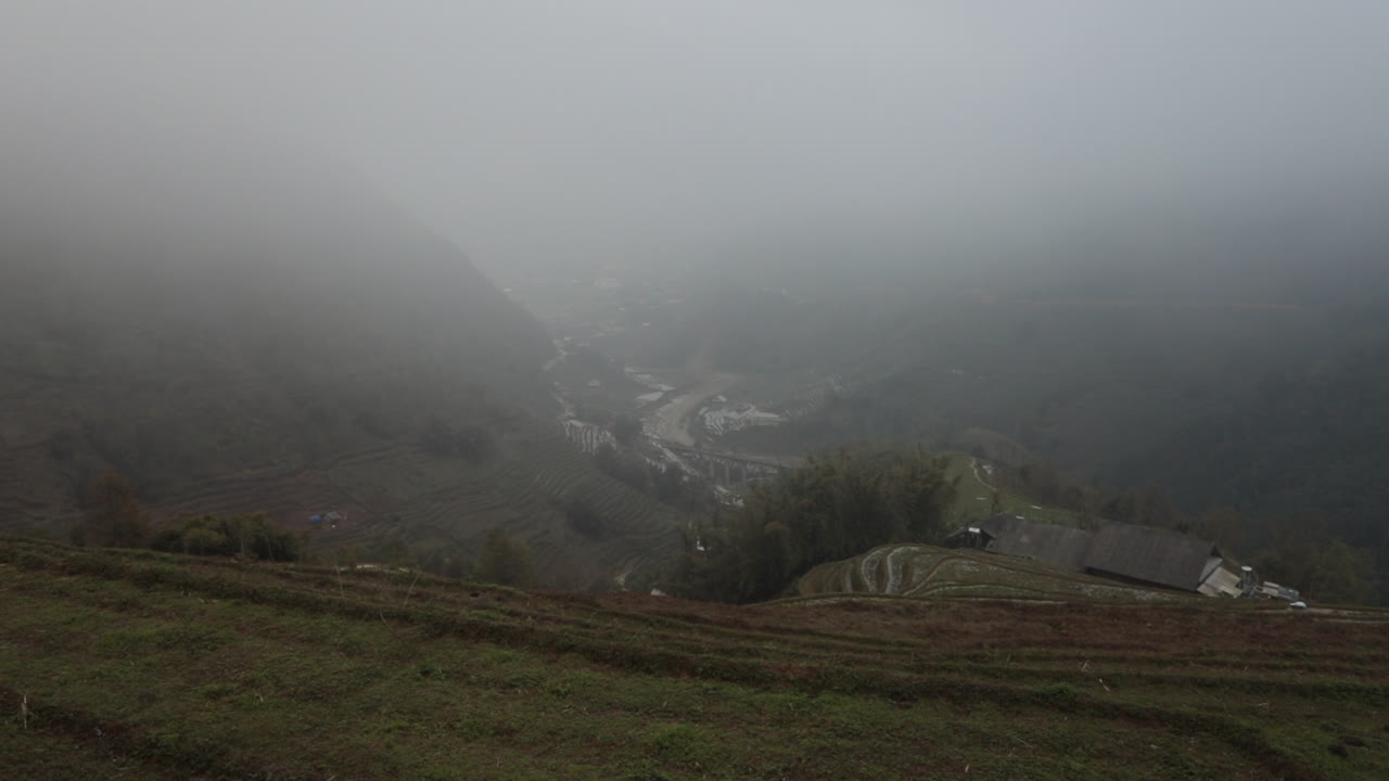 Foggy rice terraces and distant valley in Sa Pa, Vietnam, creating a serene and misty atmosphere