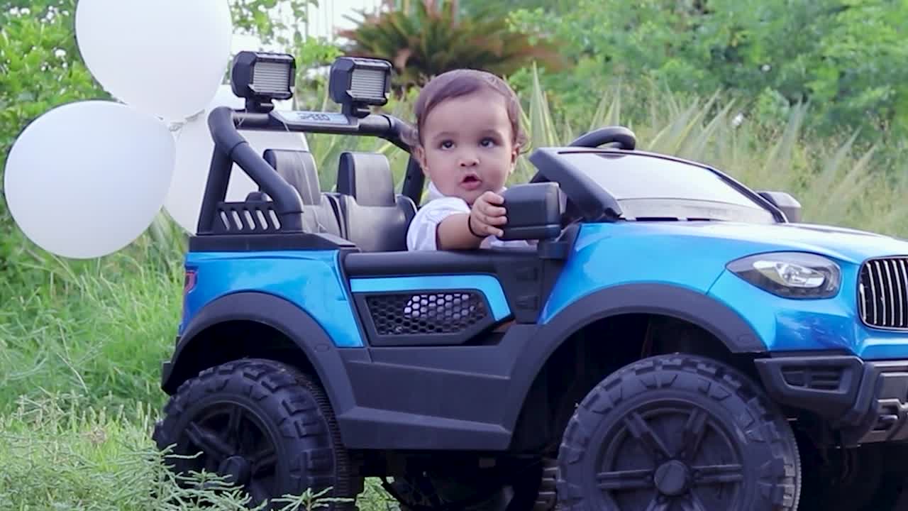 un bambino carino isolato seduto in una macchina giocattolo e che regola lo specchio all'aperto