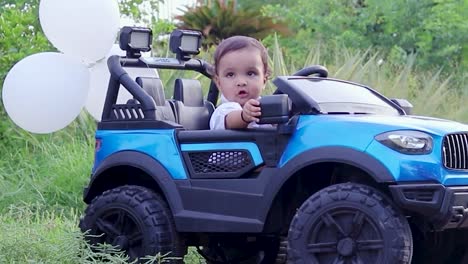 isolated cute baby boy toddler sitting in toy car and adjusting the mirror at outdoor