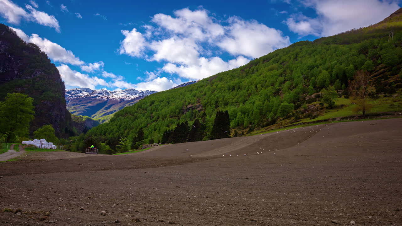 Timelapse of mountainous farmland being prepped by tractors