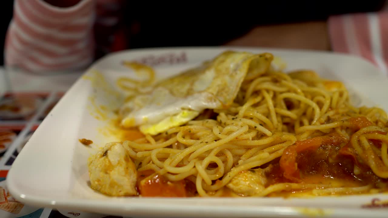 레스토랑에서 스파게티를 가까이 쳐다보면, 흐릿한 배경은 작은 소녀가 식사를 하고 있다.