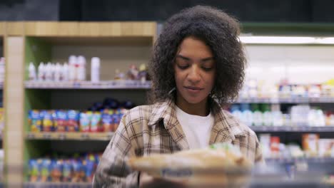 Curly-woman-taking-corn-flakes-from-the-shelf,-reads-ingredients-on-packs