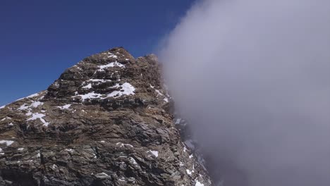 peak of mount cervino, the matterhorn, with clouds covering one face and blue sky background