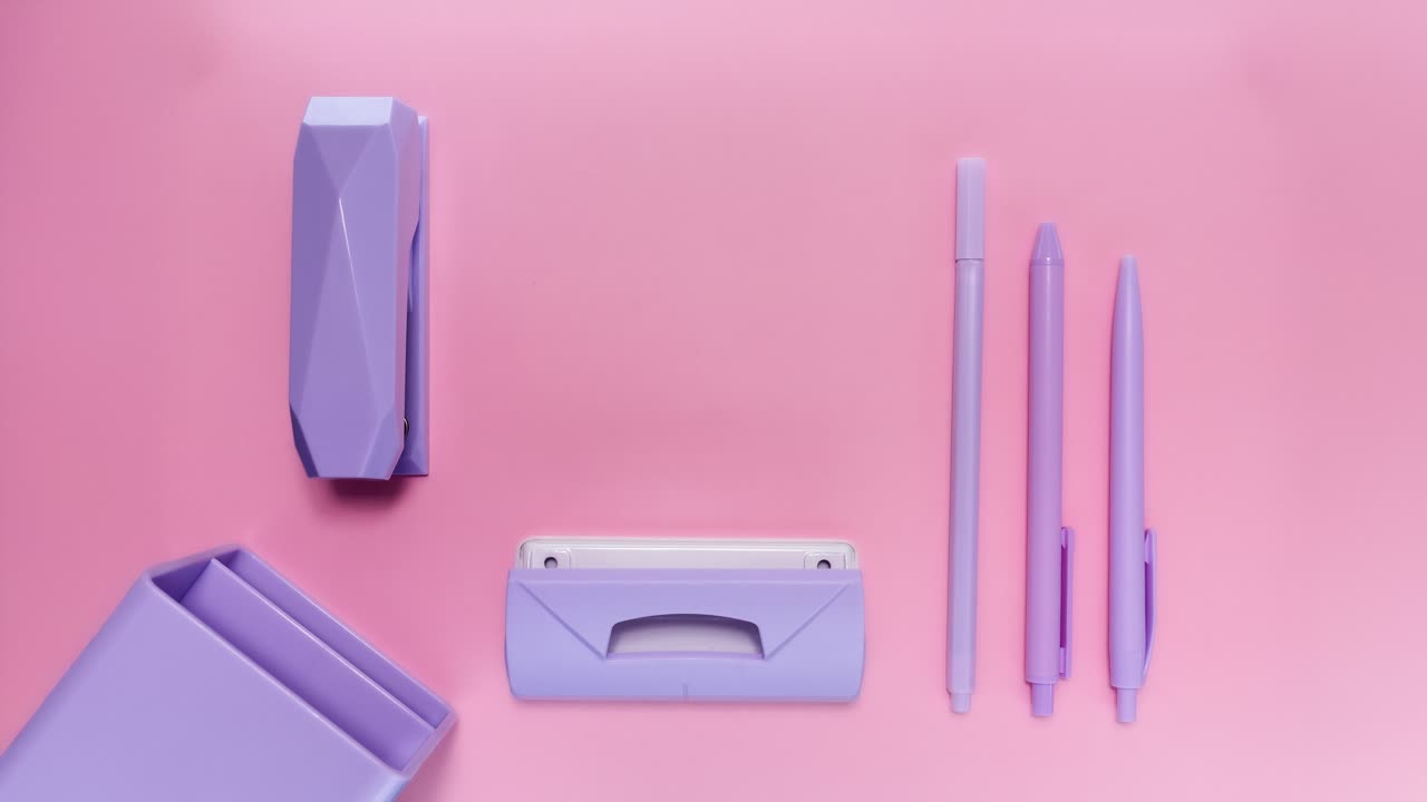 Looping stop motion reveals stationery unfolding from a desk organizer onto pink background with copy space