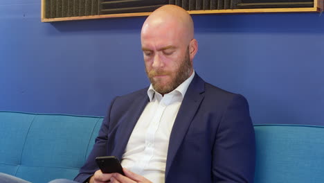 serious business man looking at mobile cell phone while sitting on sofa