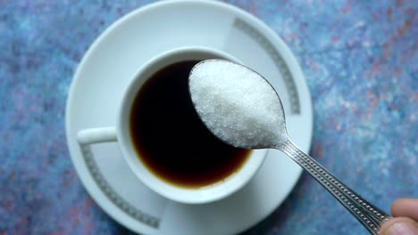 a spoon of sugar over a cup of coffee