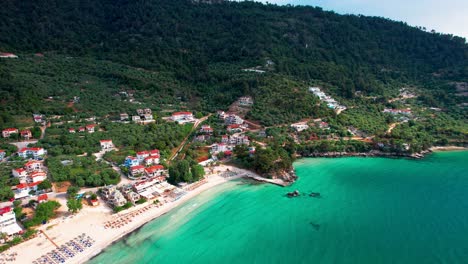 drone camera slowly tilting down to reveal the beautiful golden beach with turquoise water and lush vegetation, thassos island, greece, europe