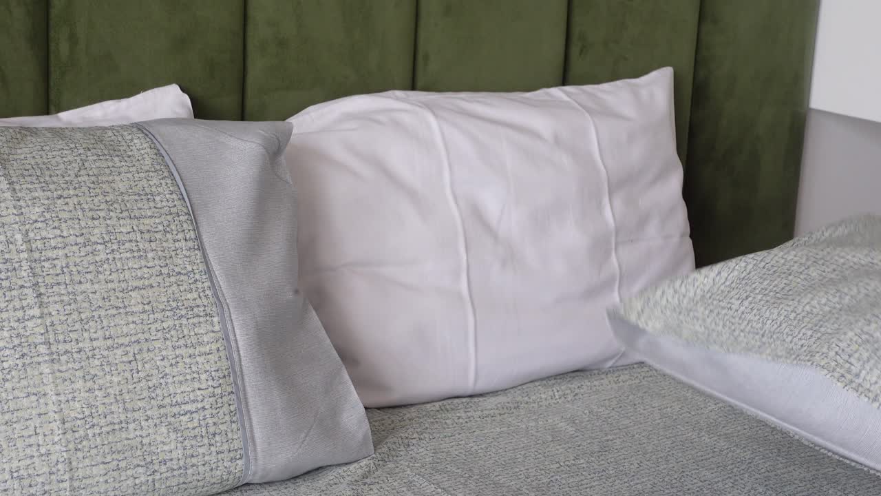 крупный план кровати с белыми подушками на зеленой головной доске