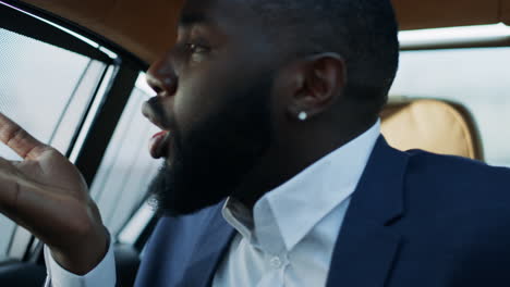 Portrait-of-african-man-blowing-kiss-at-backseat-at-car.-Business-man-flirting