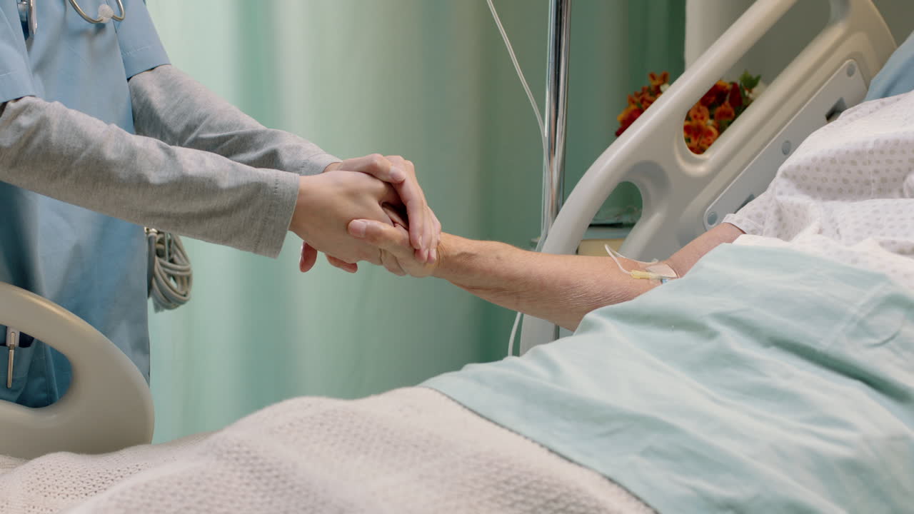病院の看護師は,ベッドで老婦人の手を握り,高齢の患者を慰め,病気から回復する病院に入院した医療従事者は,ベッドサイドで励まし,医療支援を提供します.