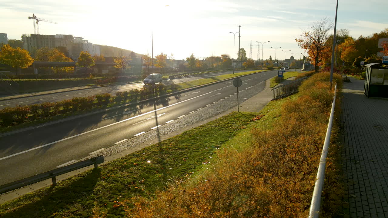 автомобили едут по дороге с двусторонним движением рядом с железнодорожной станцией с красивым пейзажем на восходе солнца в гдыне, северная польша
