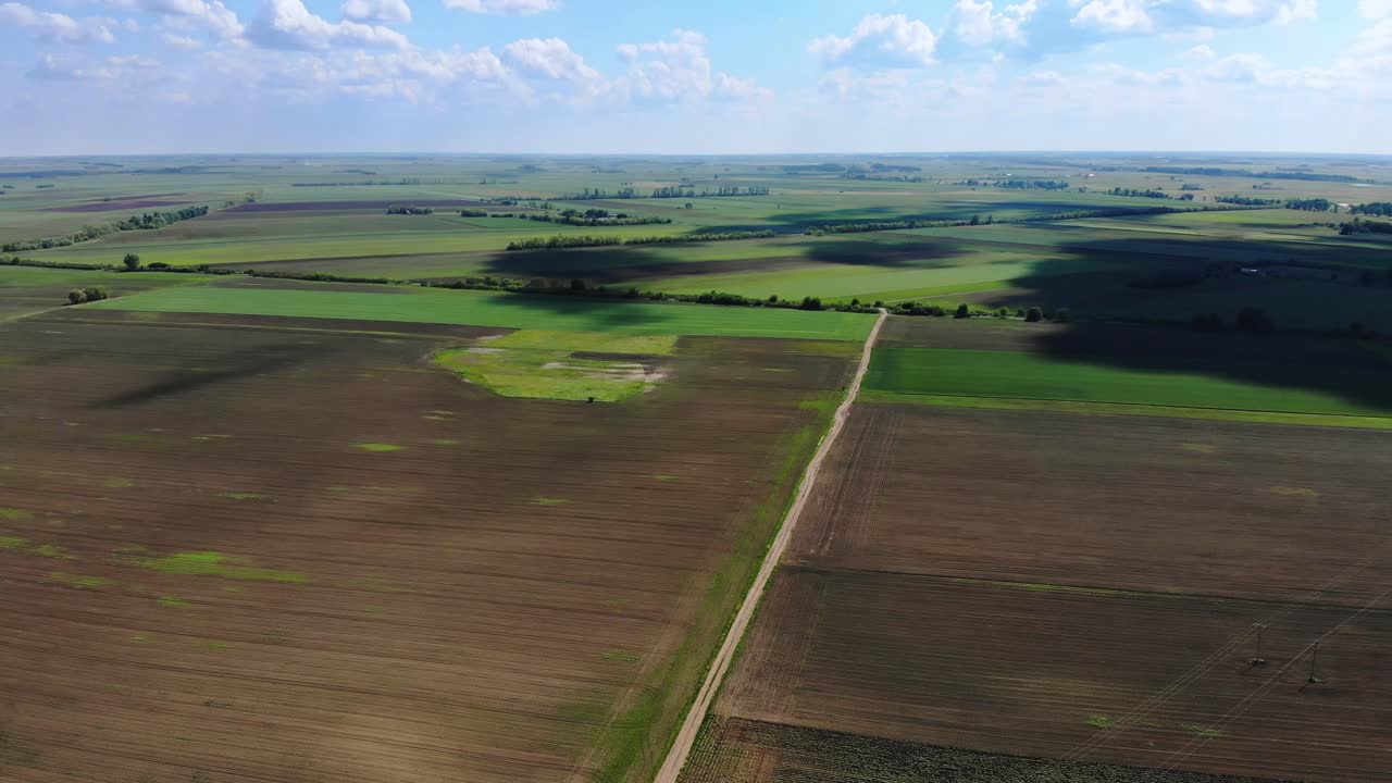 Cumulus clouds casting moving shadows on the fields, drone shot