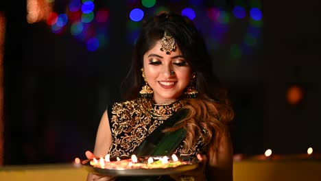 beautiful young woman lighting diya - oil lamp in traditional clothing on the occasion of diwali.