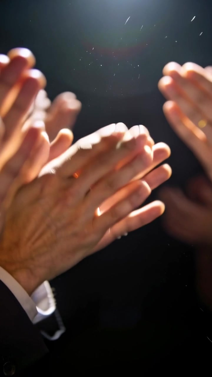 Vertical video: Clapping hands after speaker finishes at formal hall under spotlight, suit cuffs