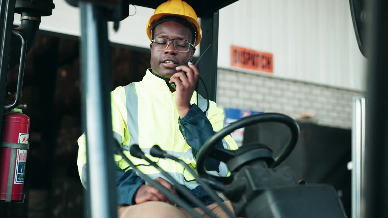 Forklift operator in a warehouse using a walkie talkie