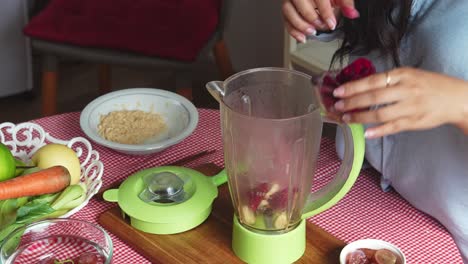 woman hands putting banana and dragonfruit sliced into blender machine