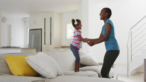 Happy-african-american-mother-and-daughter-dancing-and-having-fun-at-home