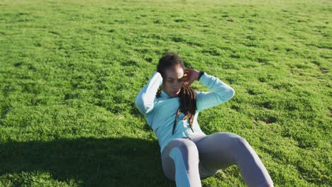 african american woman in sportswear doing sit ups in park