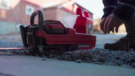 a man is adding gasoline to fuel the chainsaw - close up