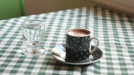 café turco y agua en un mantel a cuadros verdes
