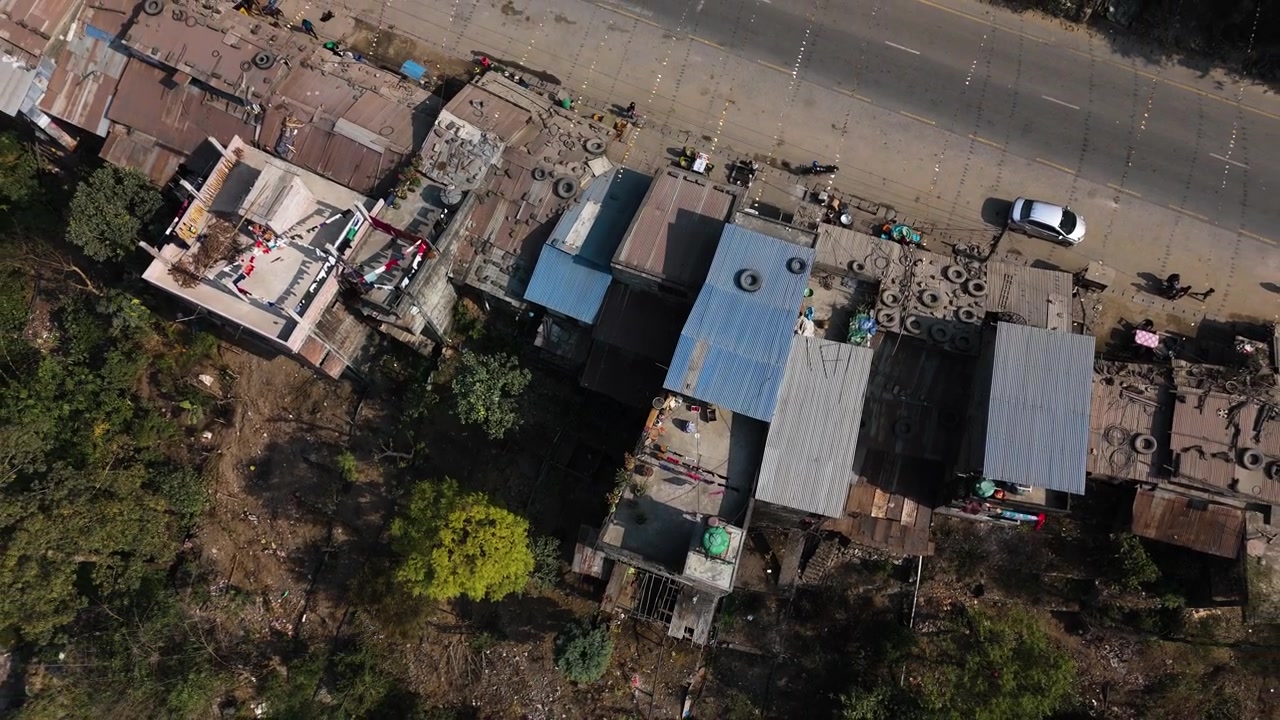 Ripresa aerea con drone che si alza davanti a case tradizionali in Nepal, giornata di sole