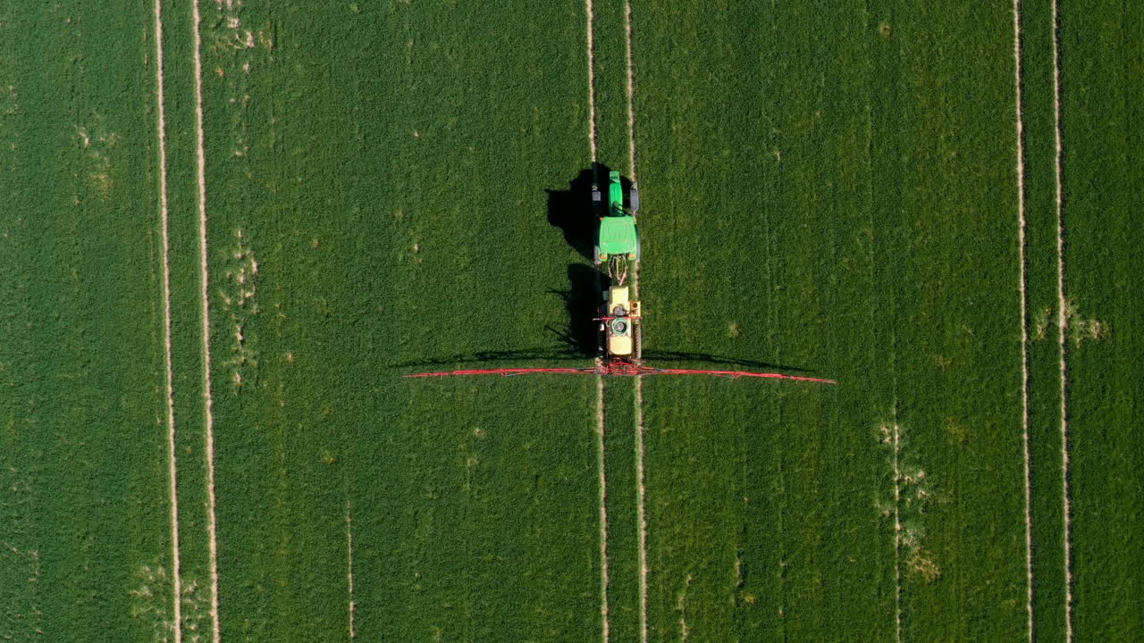 tractor rociando pesticidas en campo de trigo