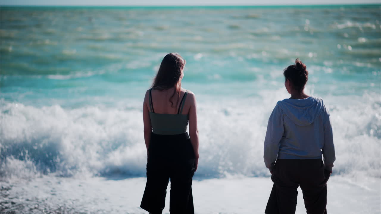 Woman looking at waves hitting the shore on the beach