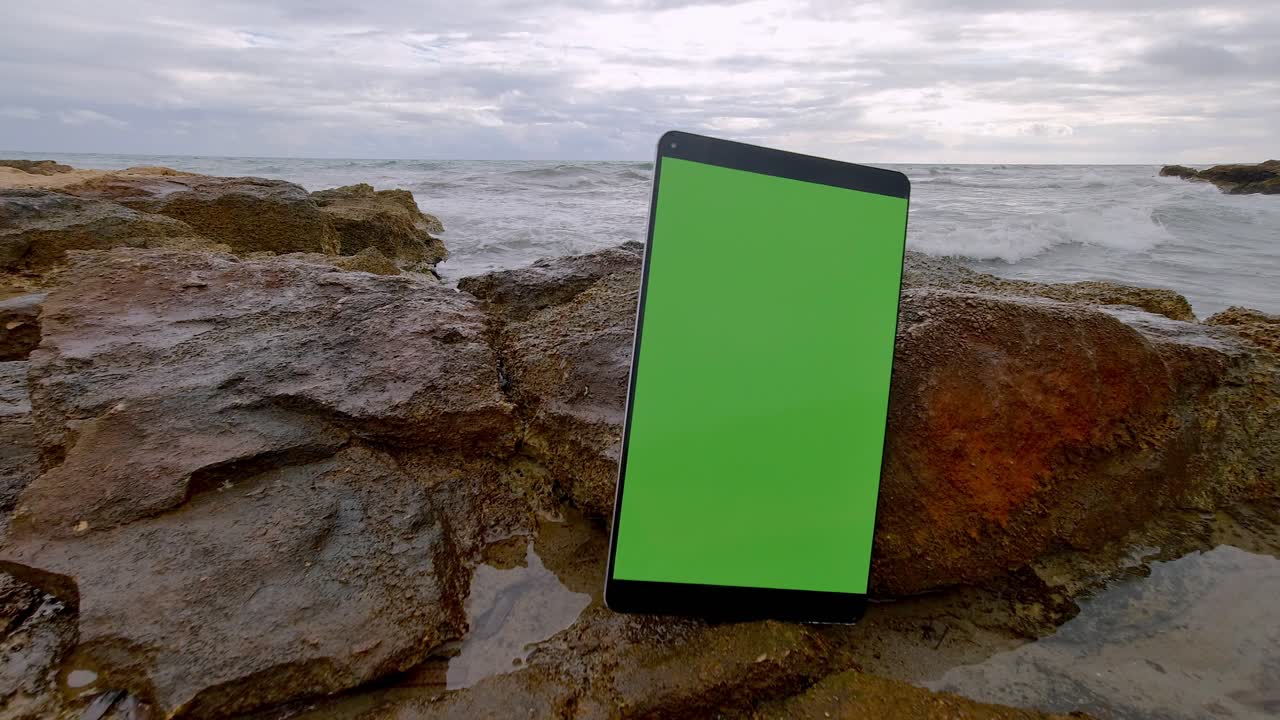 panel táctil clave electrónica tableta cromada de pie en una roca por el mar